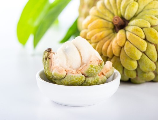 Close-up of a ripe durian fruit split open showing creamy yellow flesh inside its spiky green husk