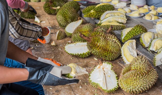 Vibrant night market in Bangkok with durian vendors displaying spiky fruits on wooden carts, illuminated by hanging lanterns